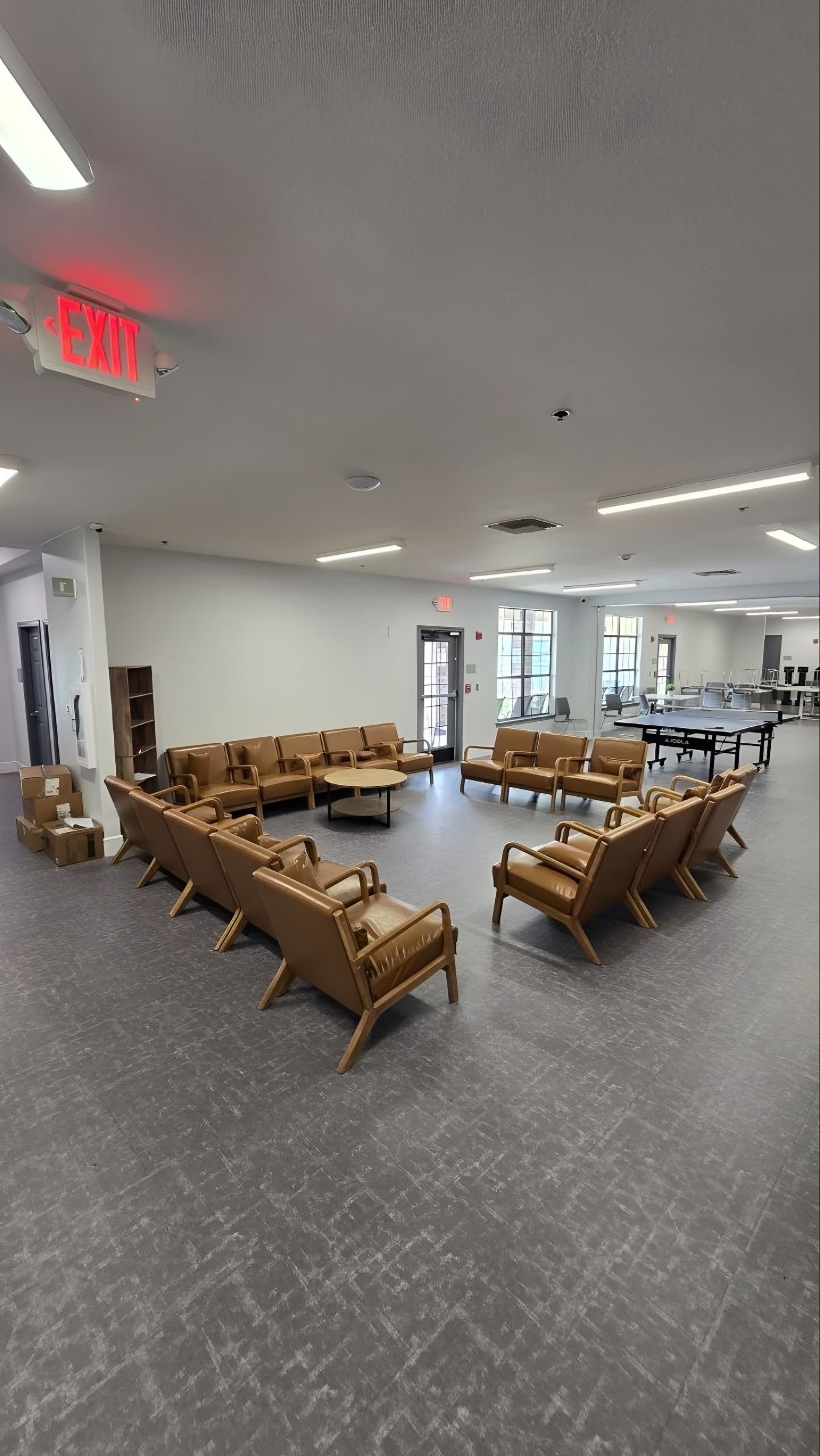 A finished common lounge in a residential treatment facility with tan leather chairs set in groups