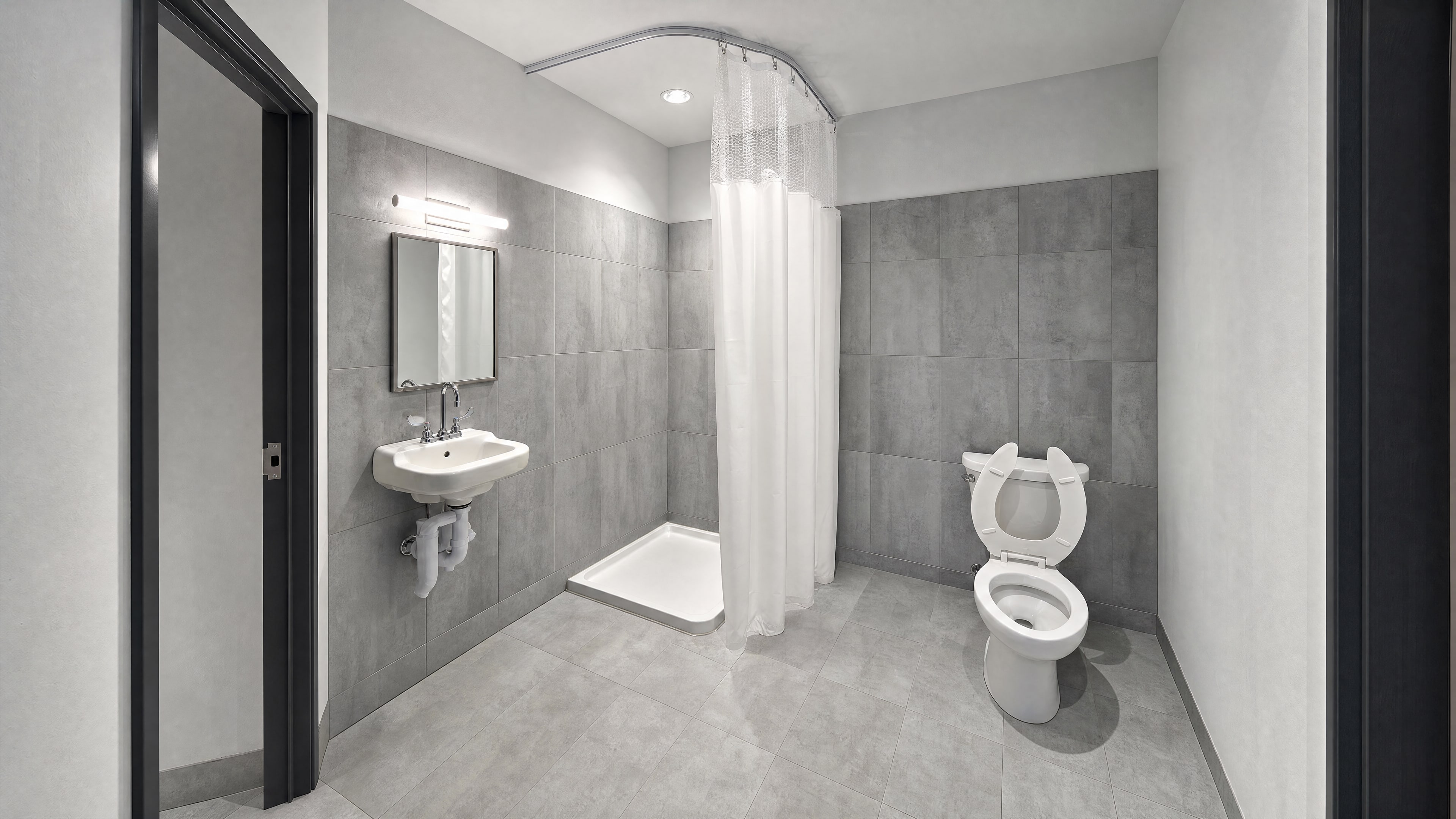 A renovated shower room in large-format grey tile with a curtained shower bay and a wall-hung lavatory