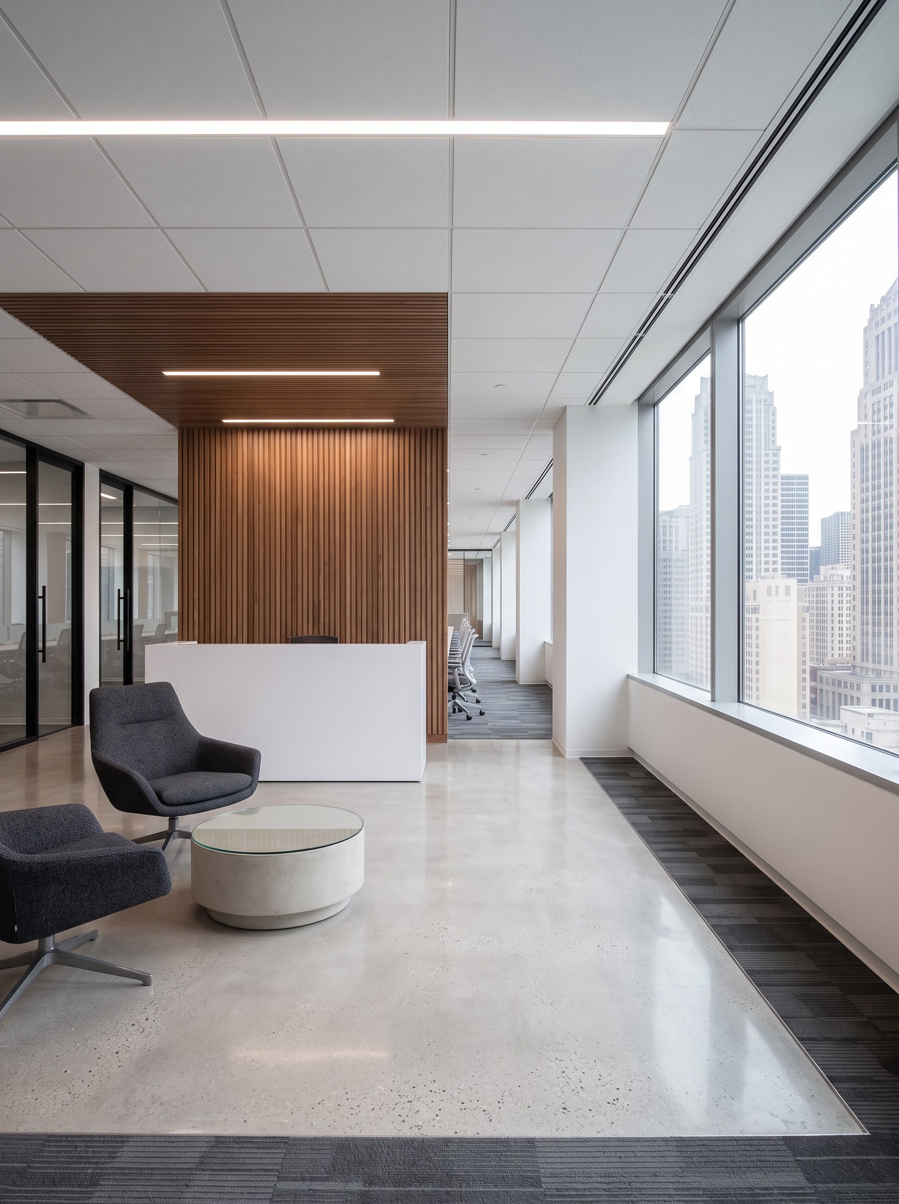 The reception: a white desk against a wood slat wall, lounge chairs and a view into the open office