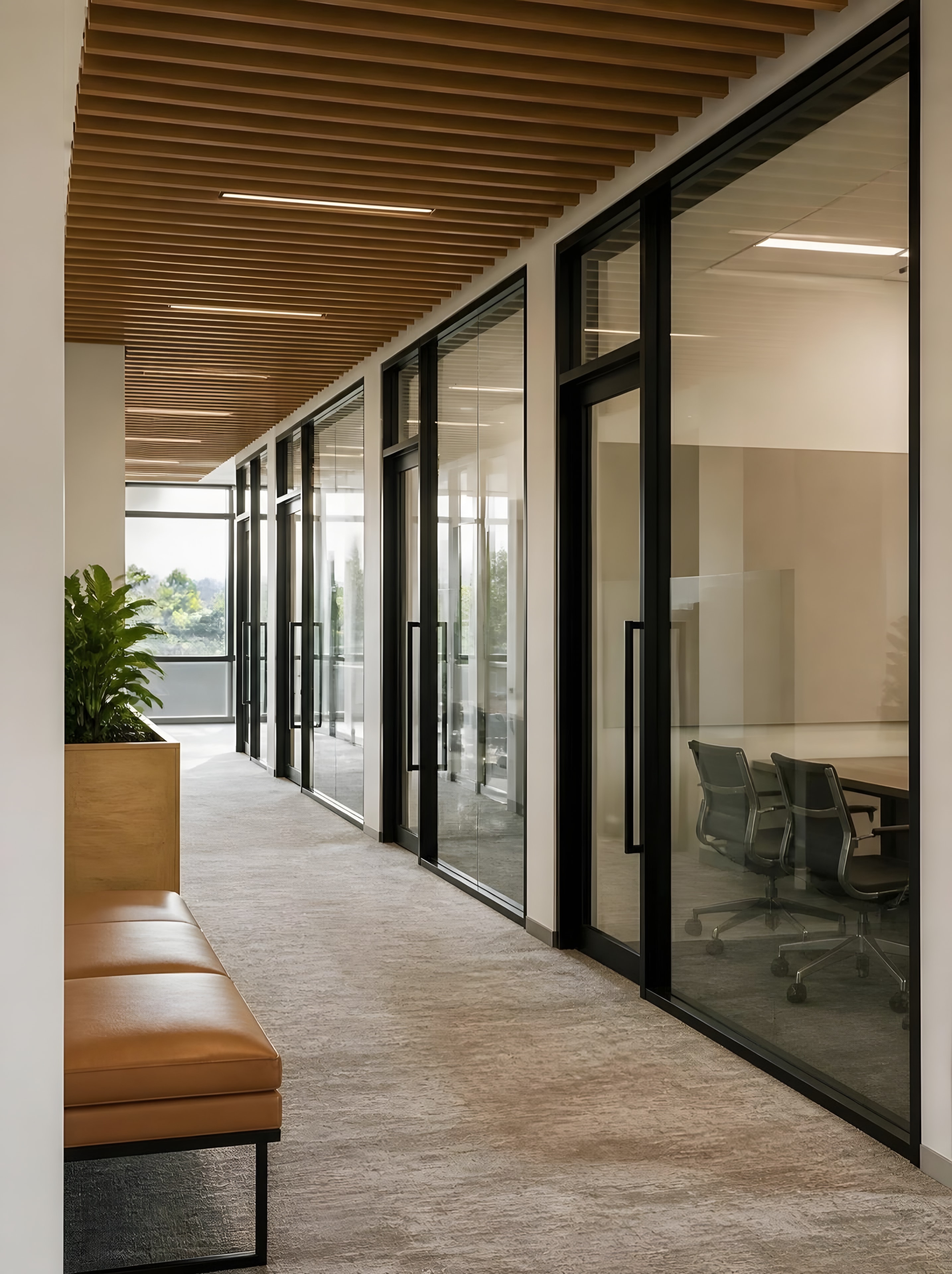 A finished office corridor of black-framed glass meeting rooms under a slatted wood ceiling
