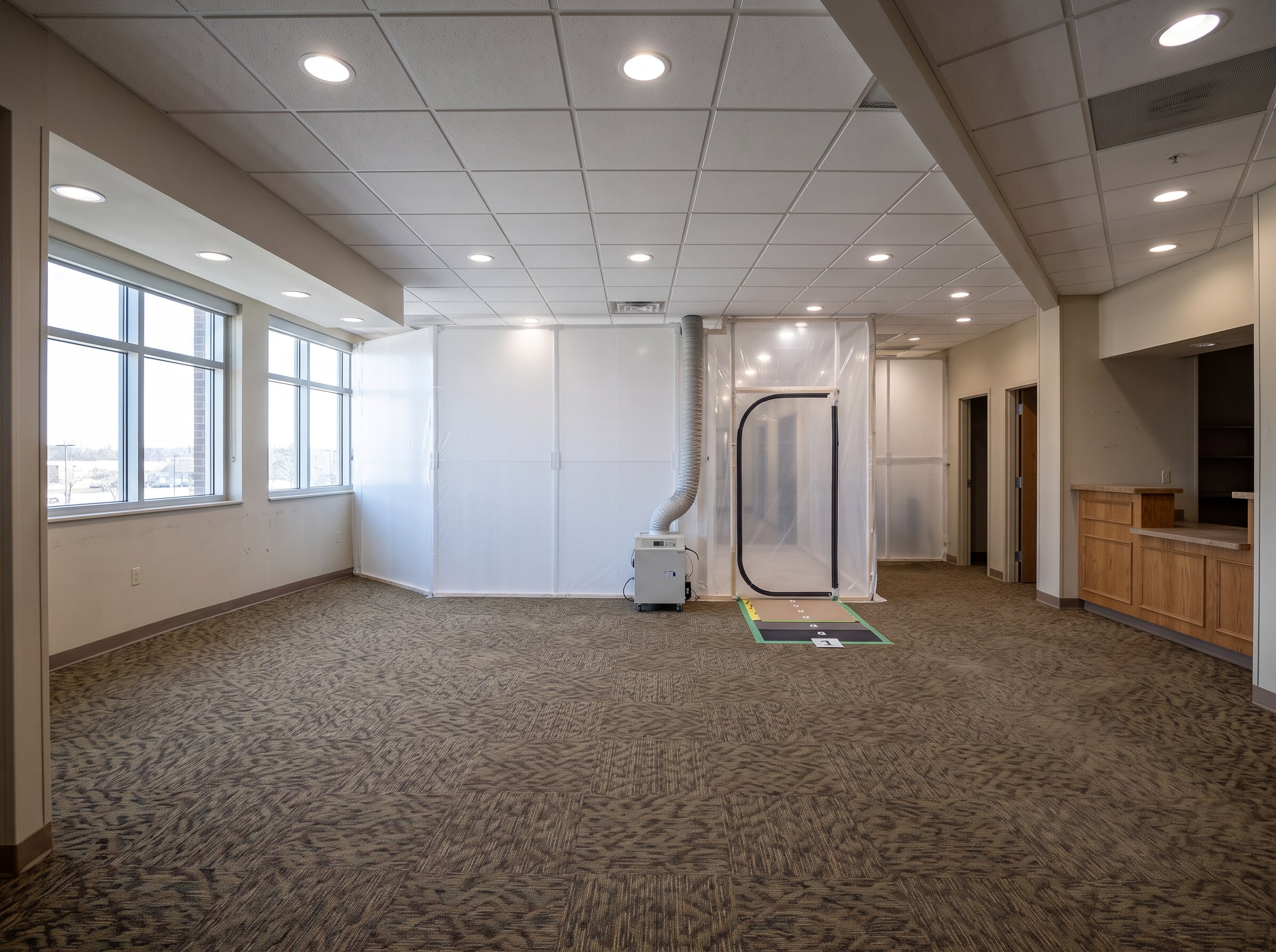 The same waiting room on the day its phase closed: a full-height dust barrier with a zippered door and a HEPA negative-air machine