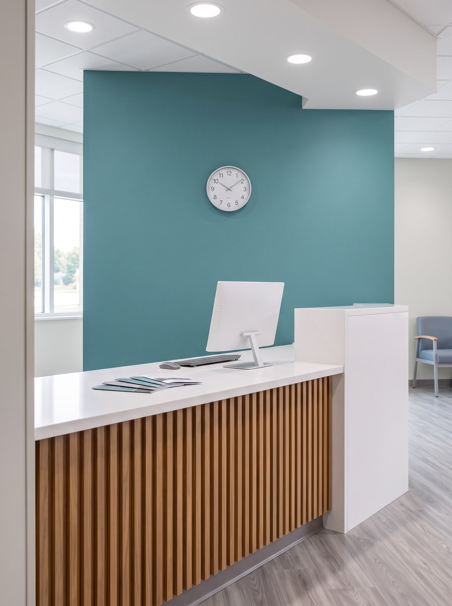 The check-in counter: solid-surface top over a wood slat front, the teal wall behind
