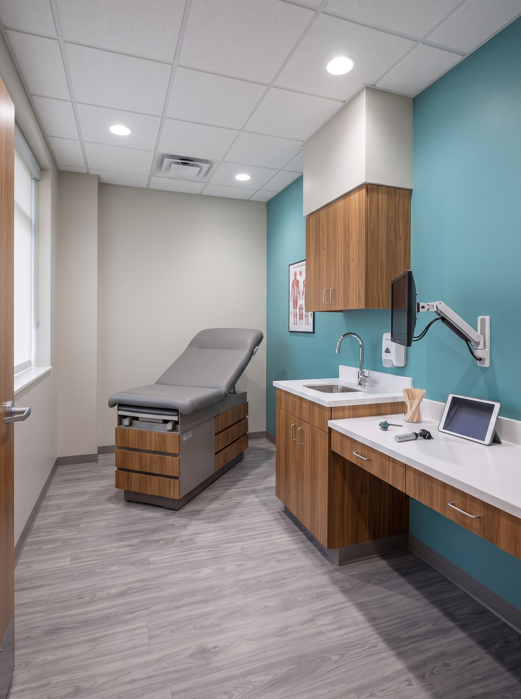 A renovated exam room: exam table, casework with a sink and the teal accent wall