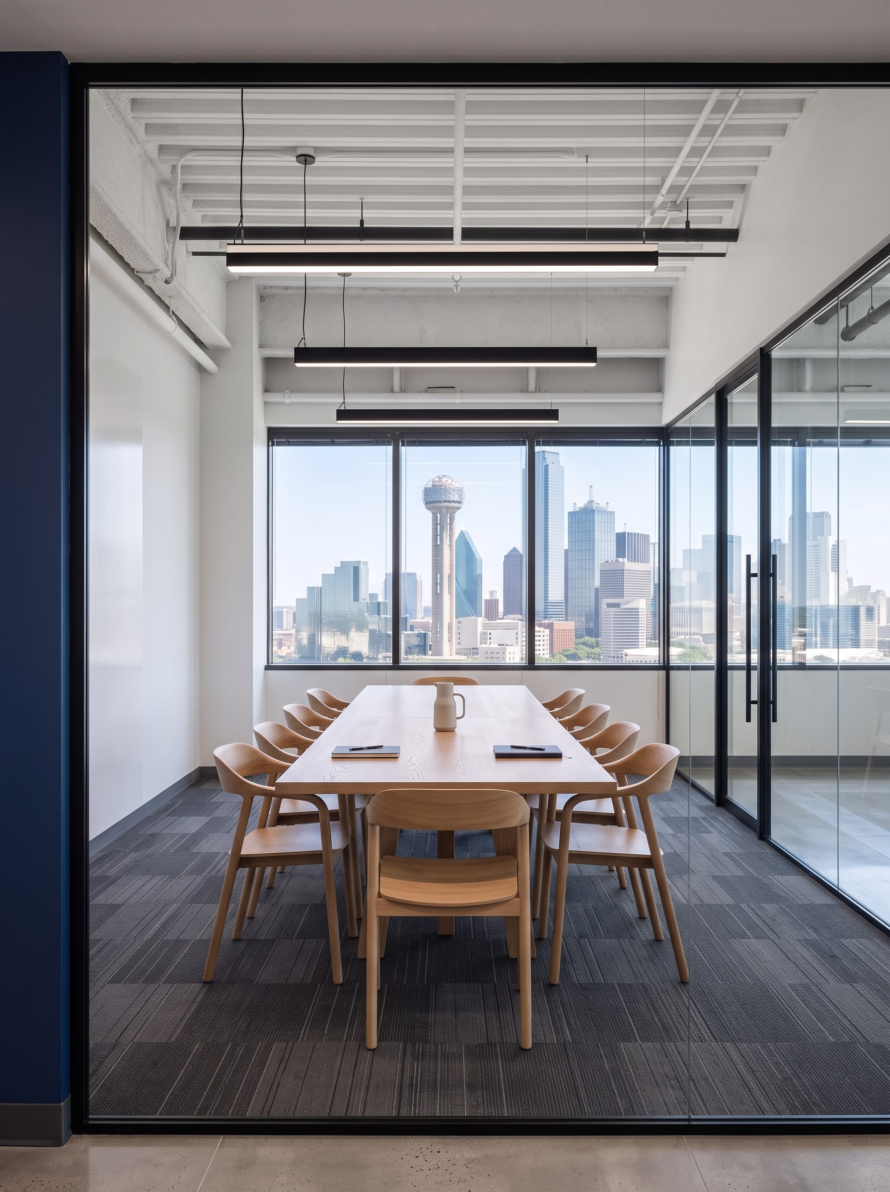 The collaboration area: a long wooden table under black pendants, the Dallas skyline outside