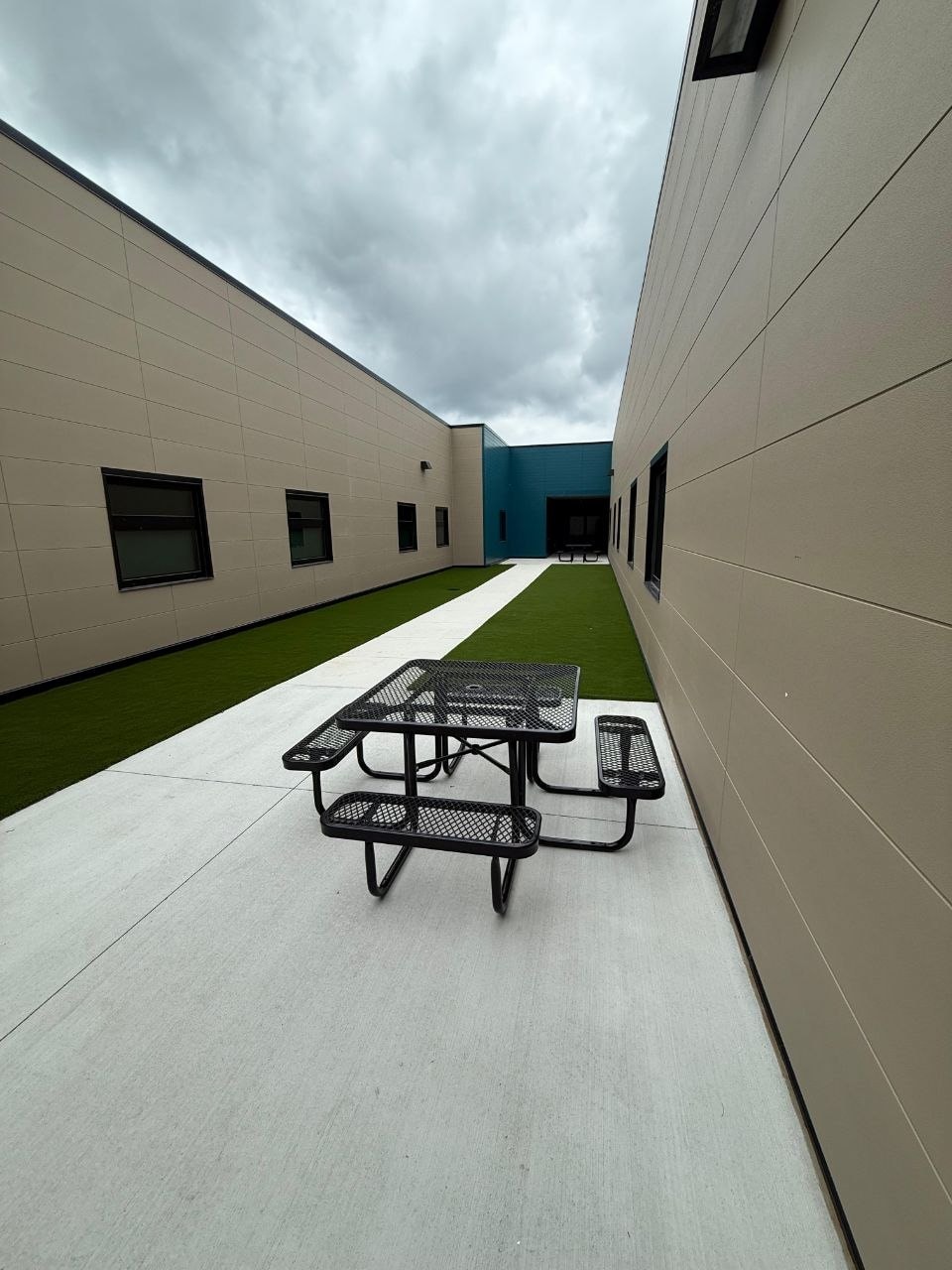 The enclosed exterior courtyard with turf, a concrete walk and a picnic table