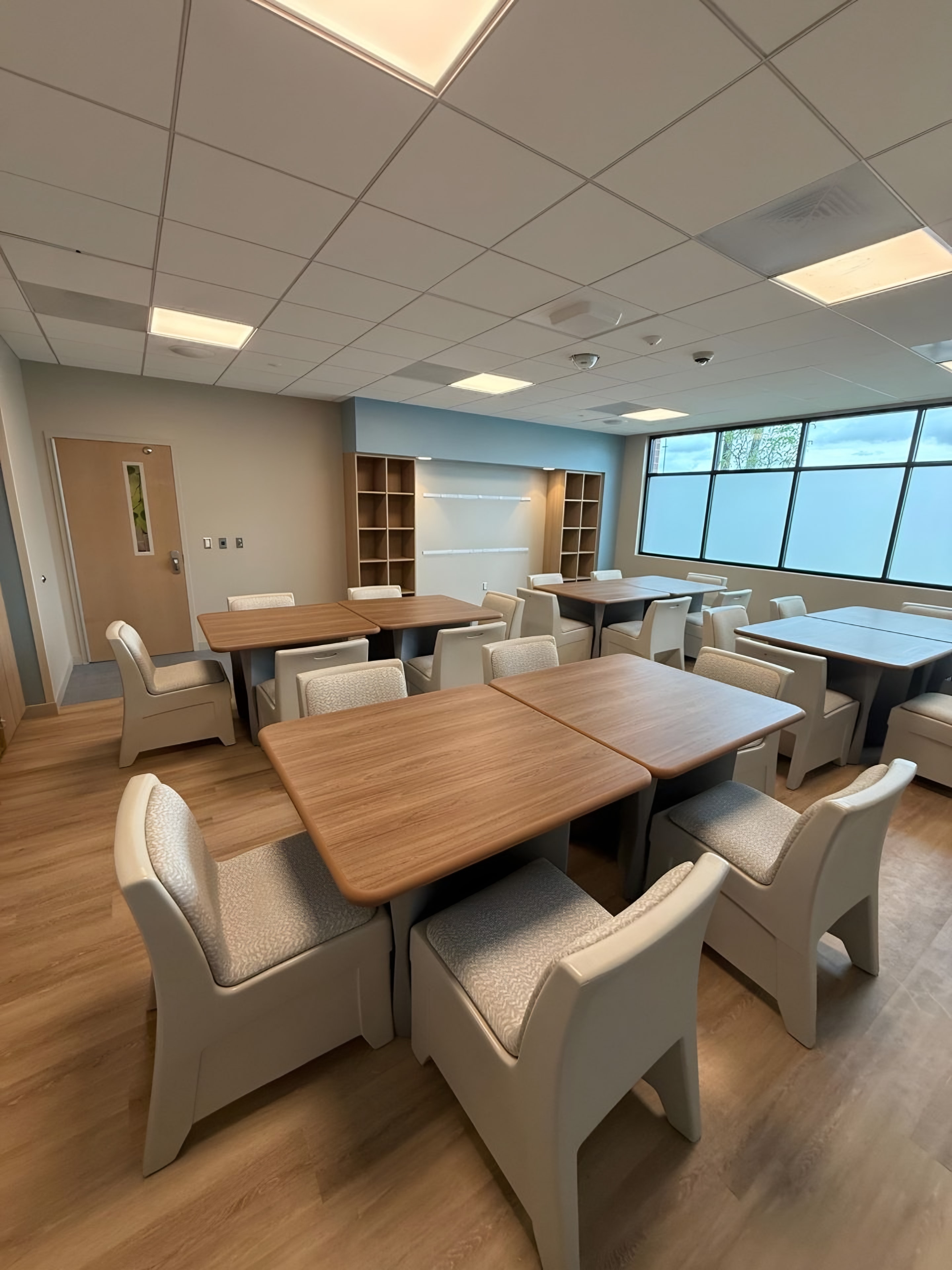 The same group room seen from the door: wood-top tables, built-in cubbies and frosted clerestory glazing