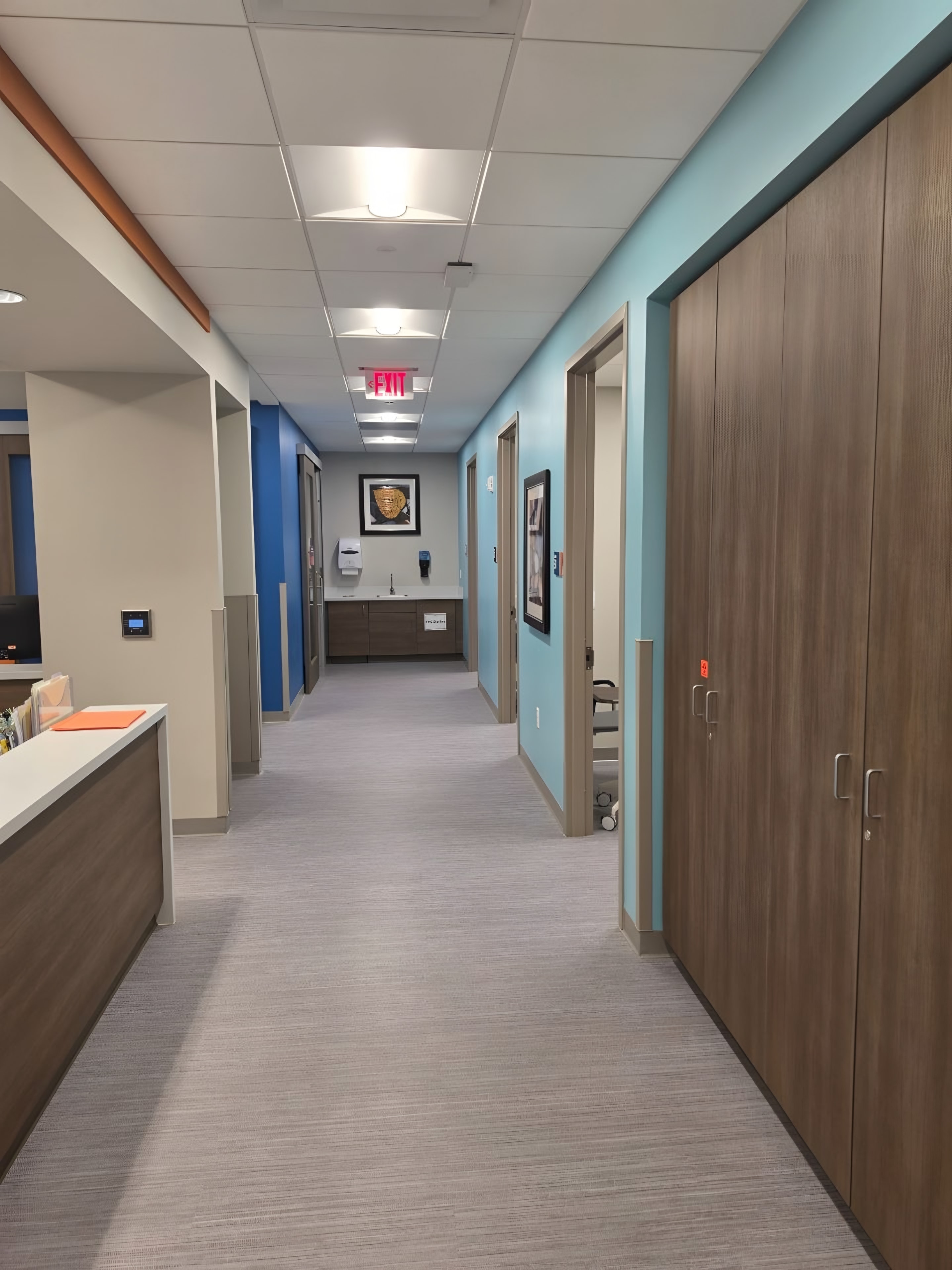 A finished clinic corridor with a painted accent wall, casework and room doors