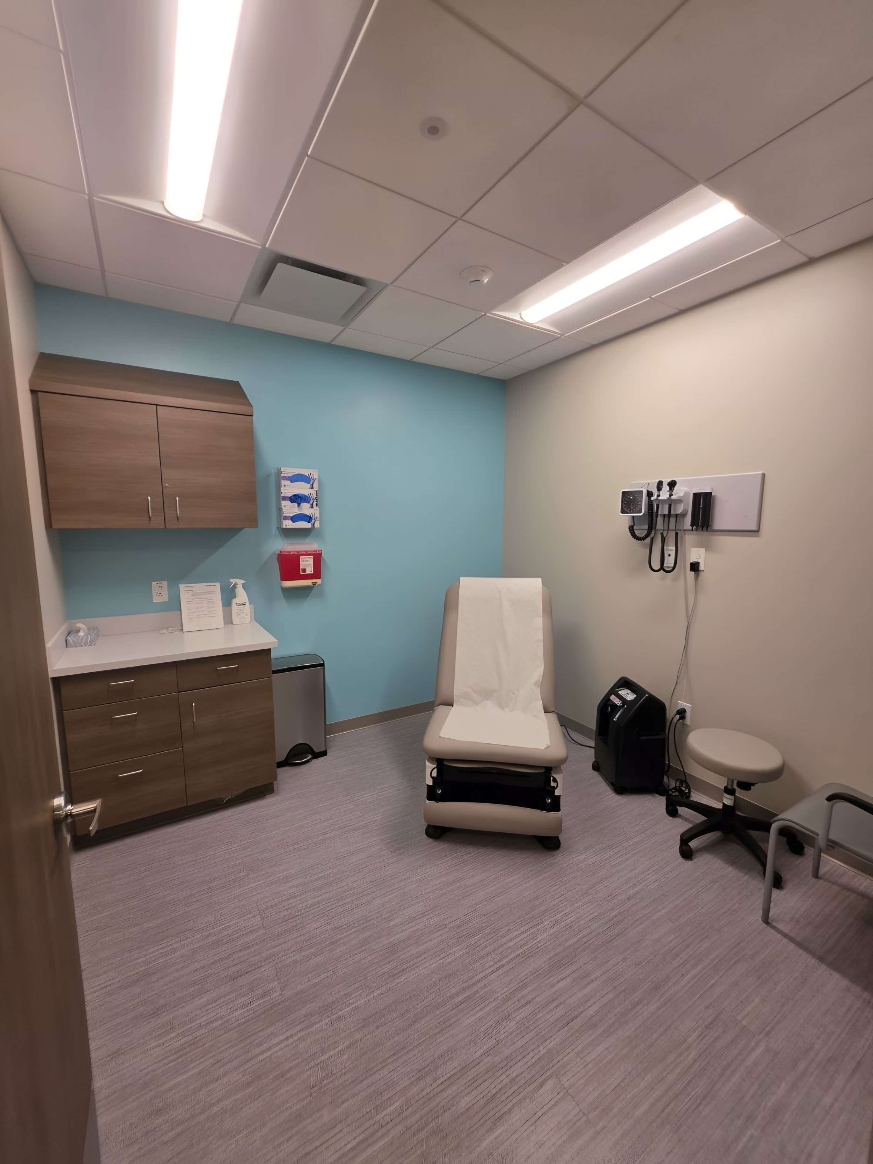A finished exam room with wall casework, an exam table and a diagnostic wall unit