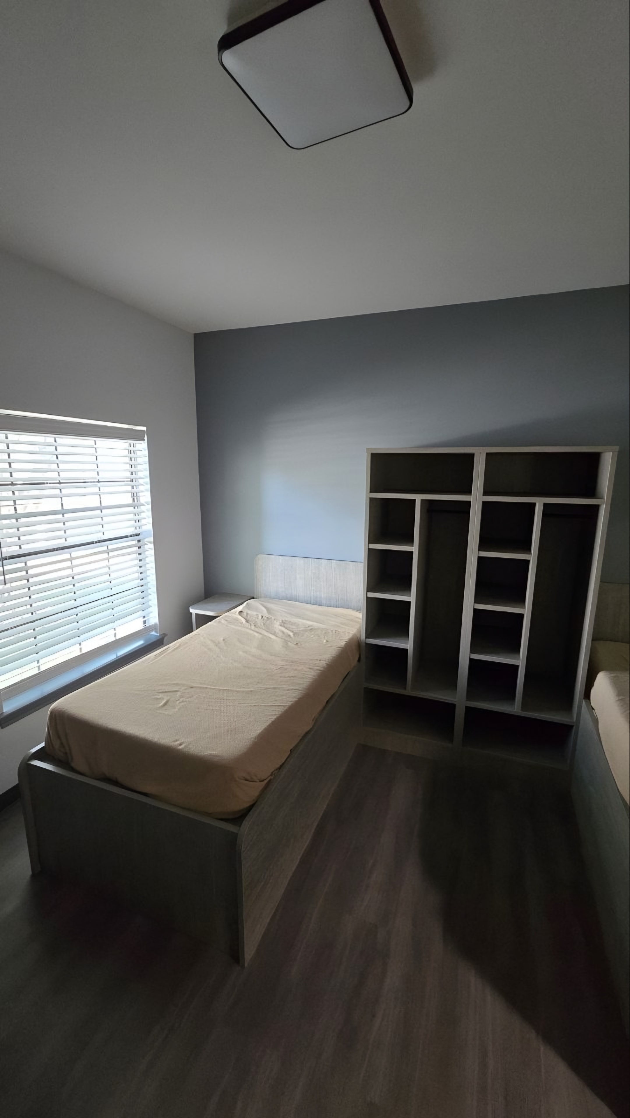 A finished resident bedroom with a platform bed and an open locker unit