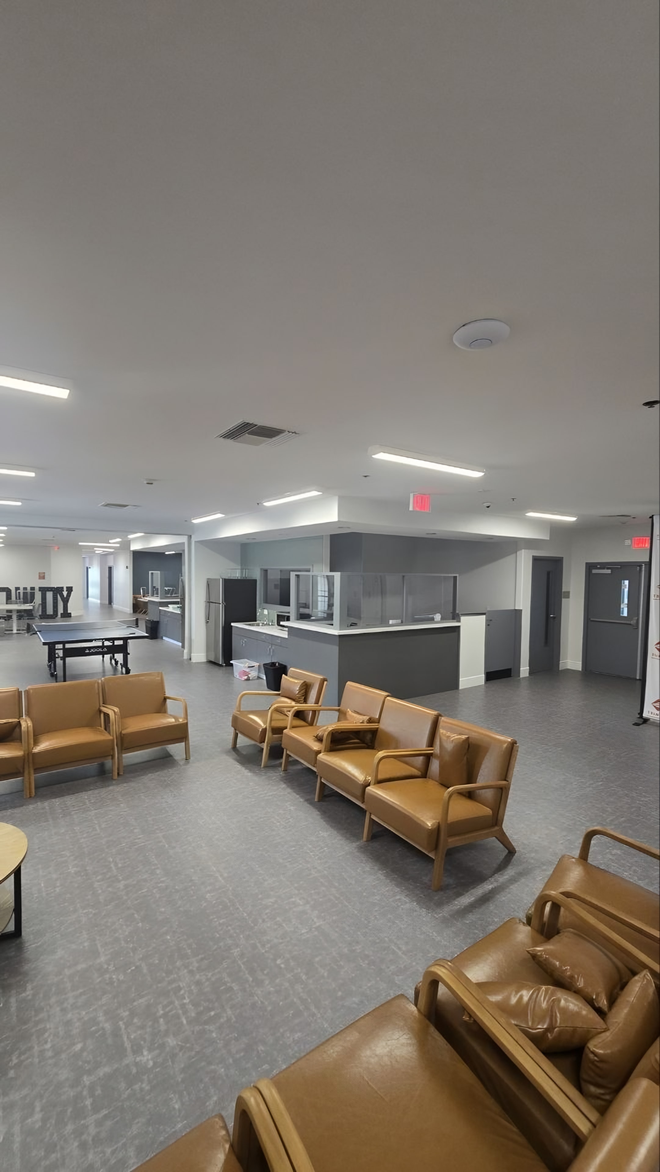 A finished common area with seating groups and a staff station behind glazing