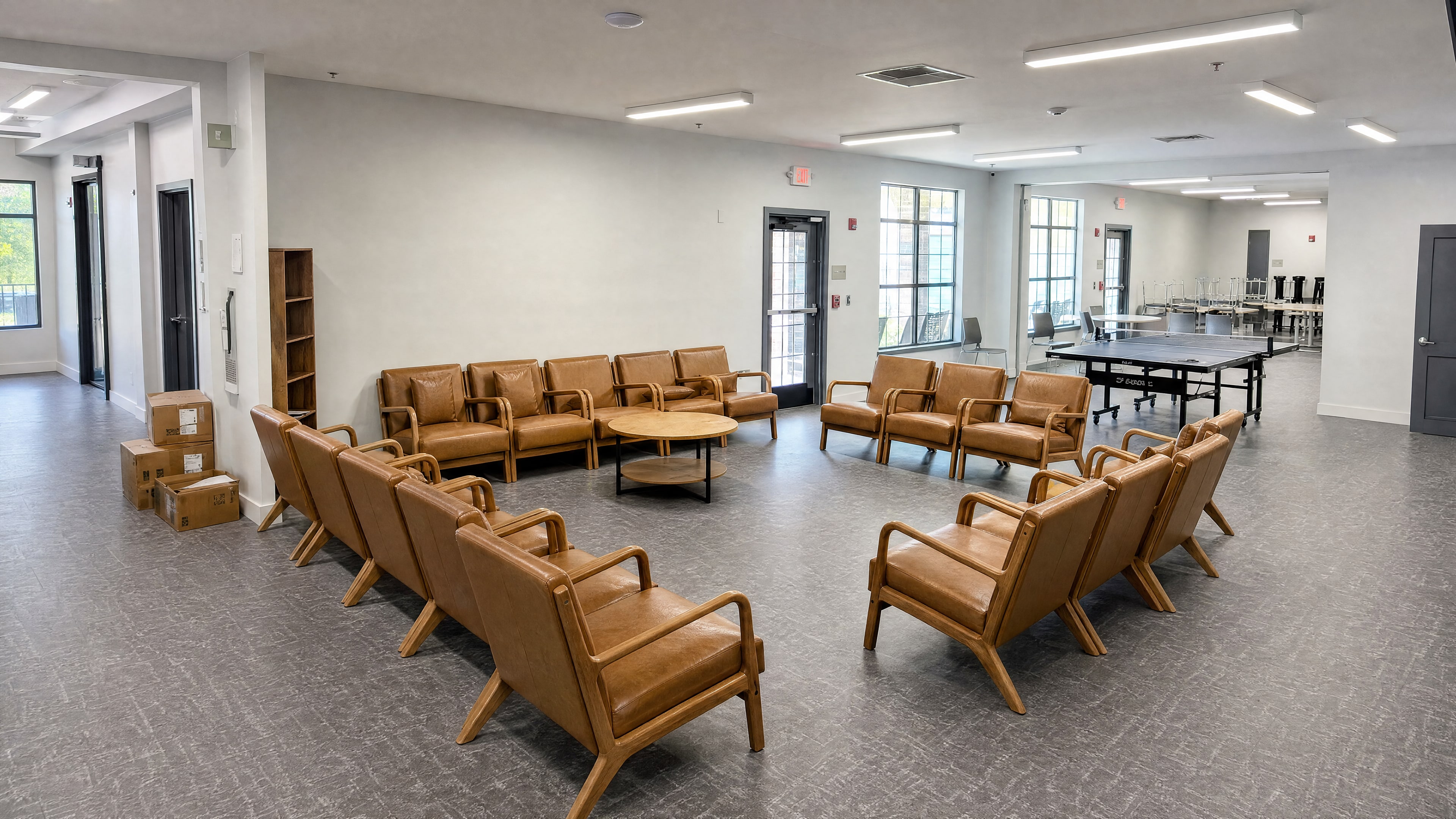 The renovated lounge with tan leather chairs in groups, a table tennis table and tall windows