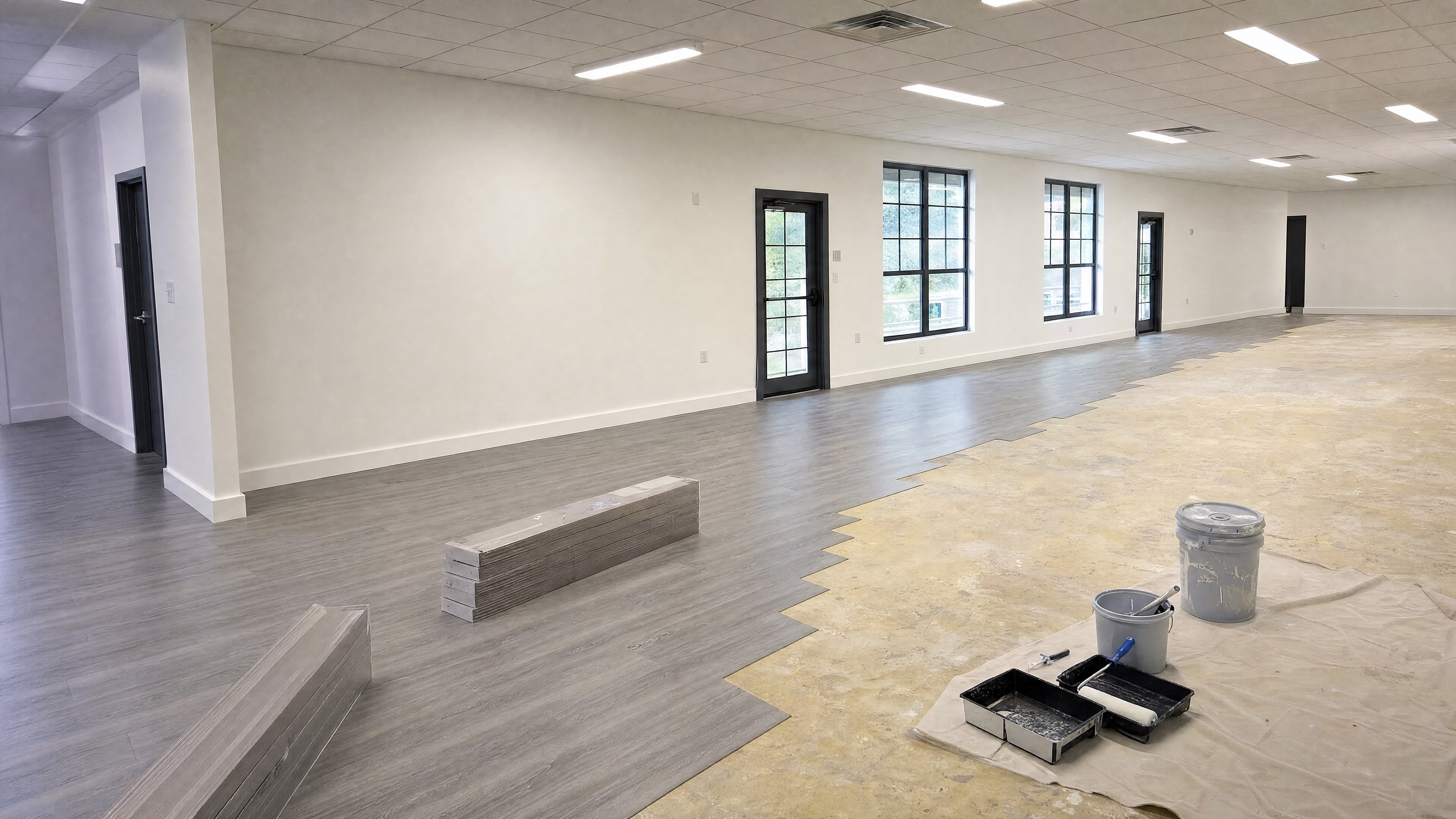 Freshly painted walls and new vinyl plank flooring being laid in the empty lounge