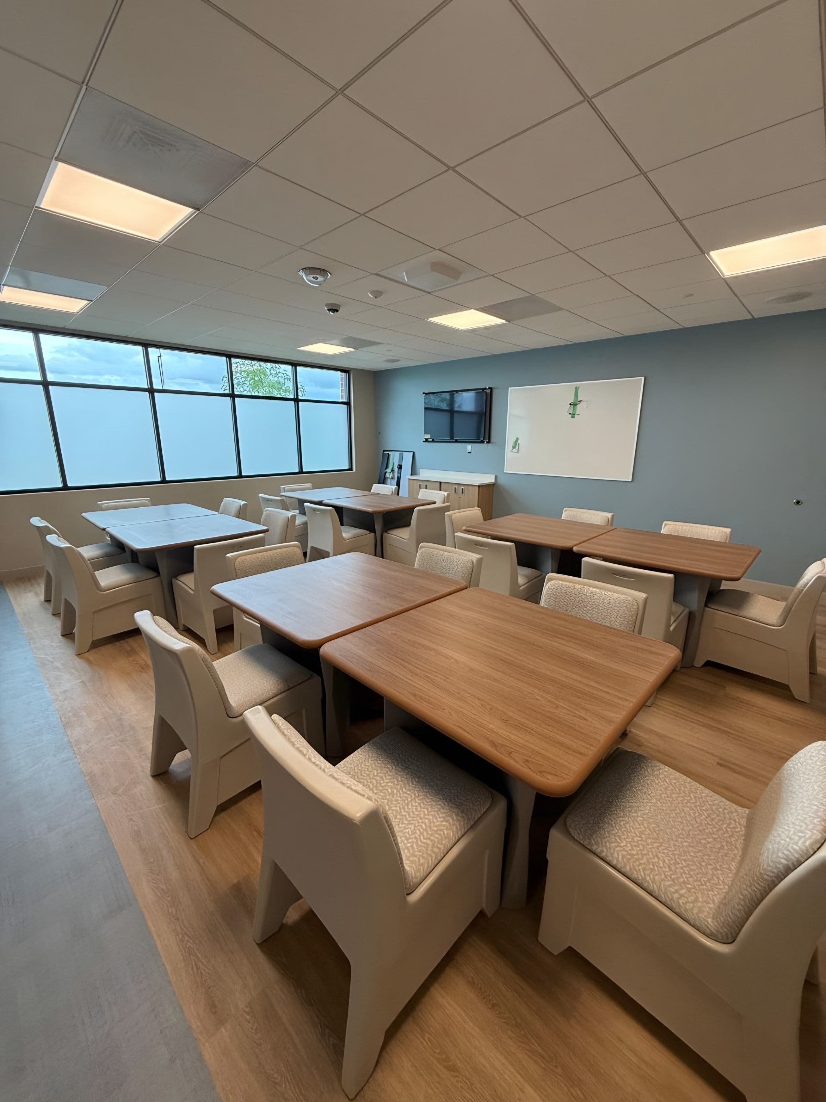 A finished group room with tamper-resistant chairs, wood-top tables and a blue accent wall