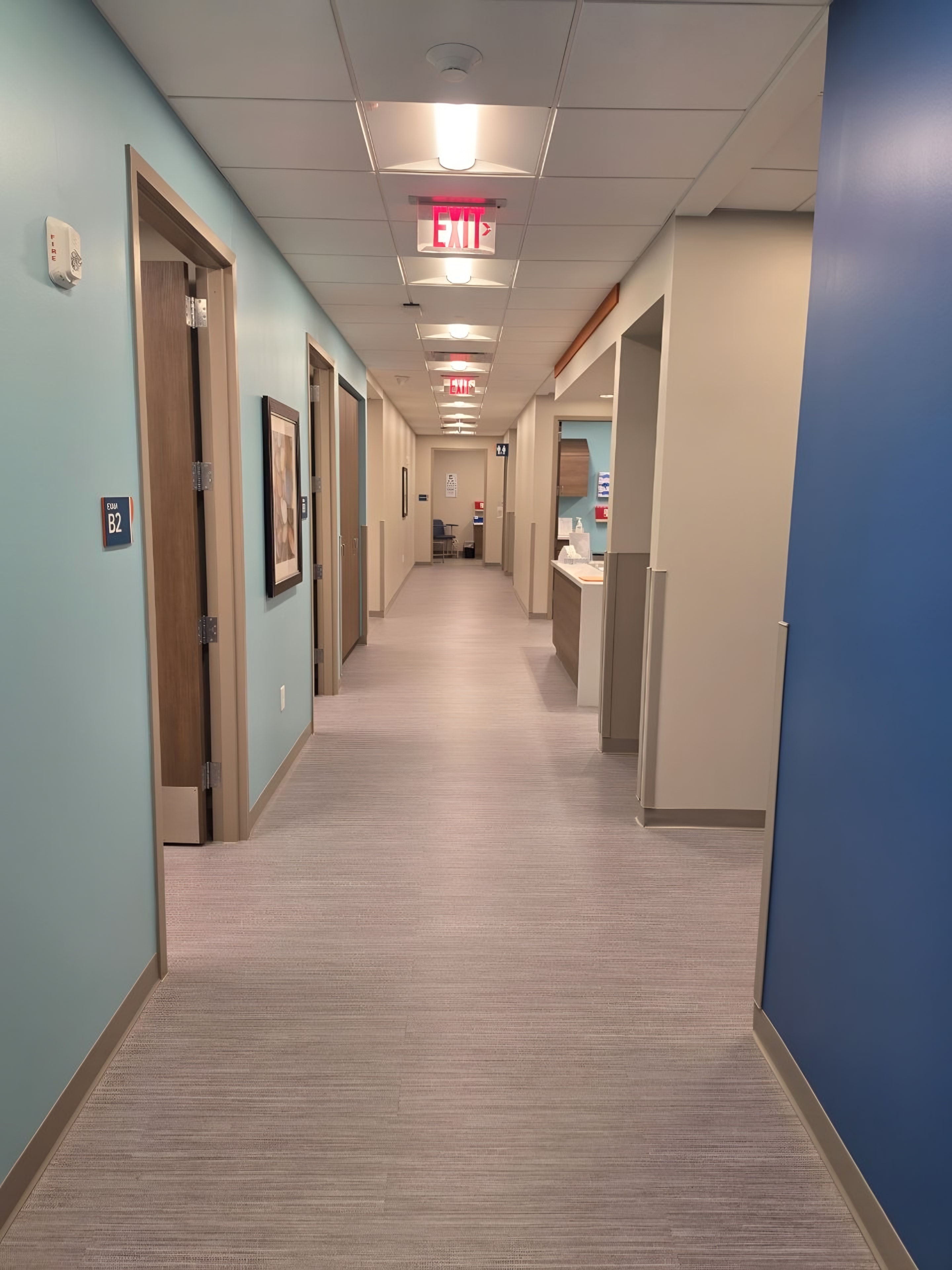 A finished clinic corridor with painted accent walls and framed art