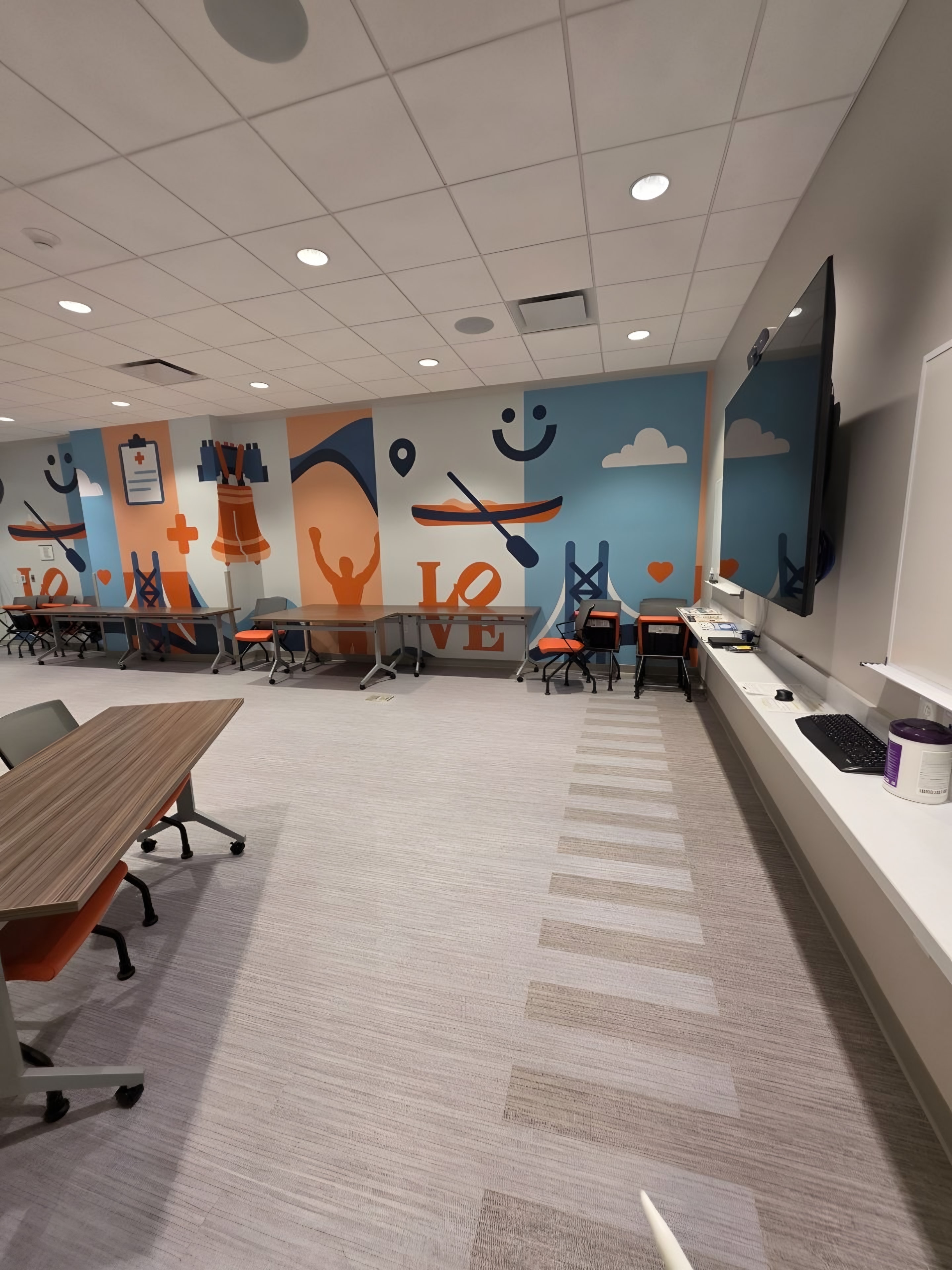 A finished training room with a painted mural wall and long tables