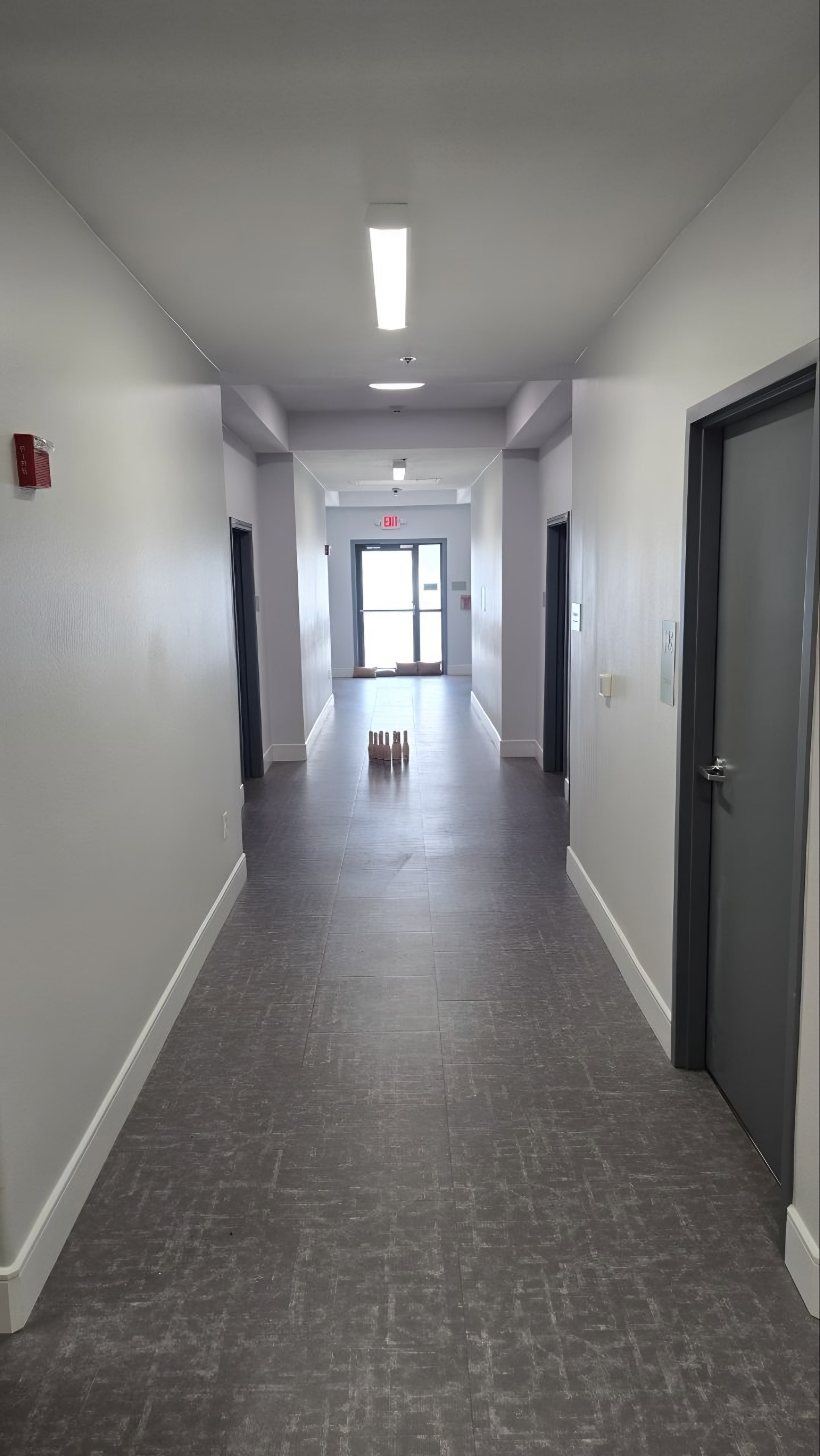 A corridor with a tile floor and a glazed exit door